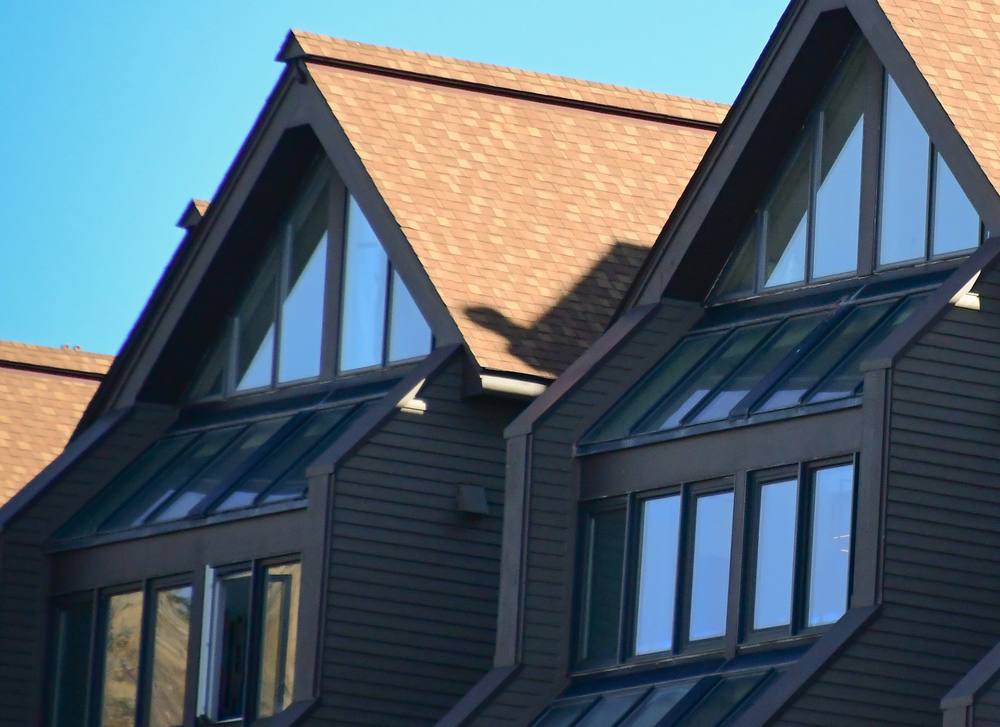 Close view of gabled dormers with tan shingles