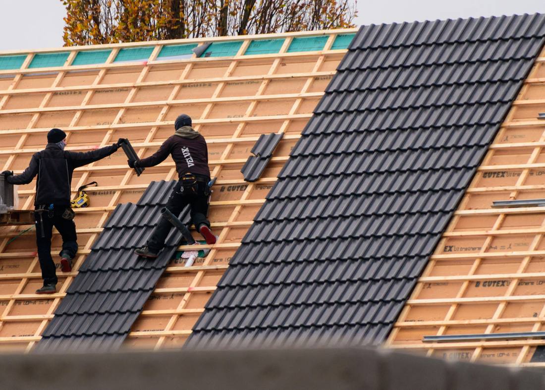 Crew installing dark roof tiles over new battens